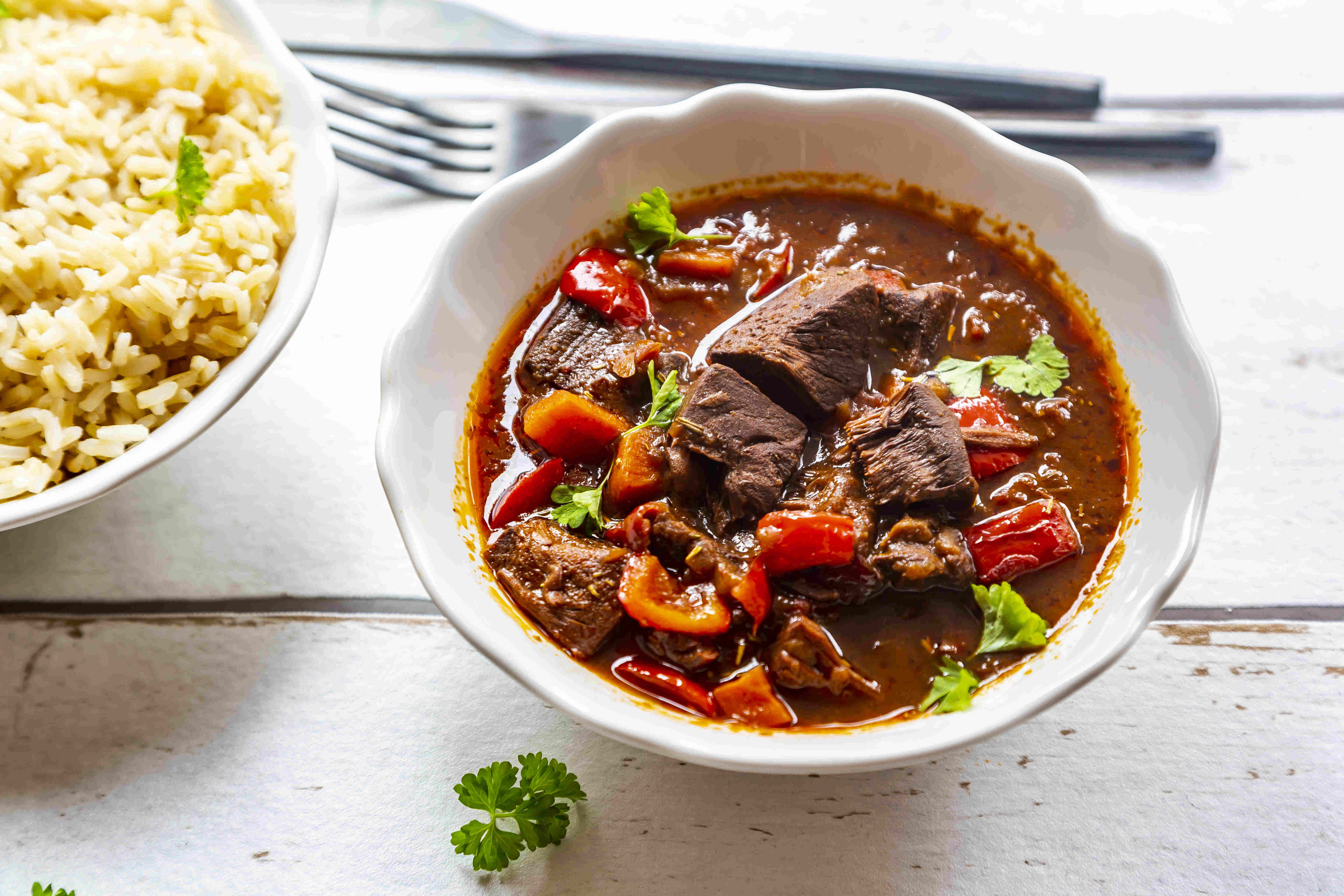 A plant-based goulash stew using jackfruit next to a bowl of brown rice.